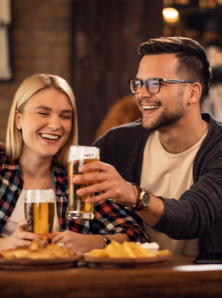 conveniencia_0001_young-happy-couple-having-fun-together-while-toasting-with-beer-bar