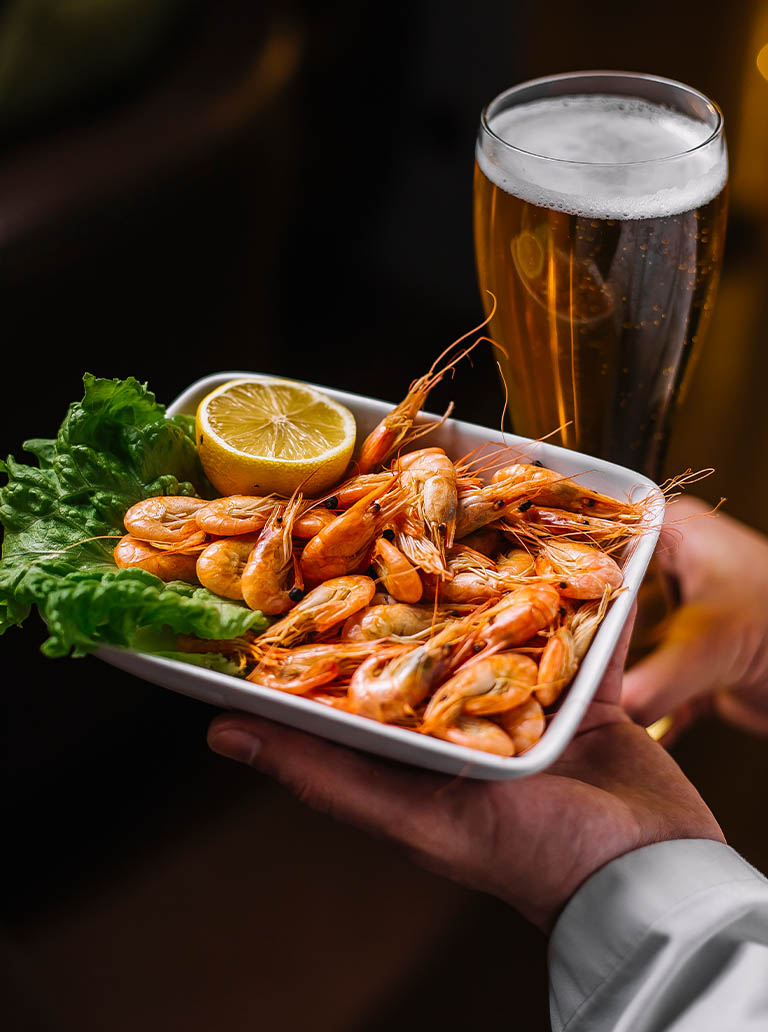 restaurante_0003_man-holds-plate-with-shrimps-lettuce-lemon-side-view